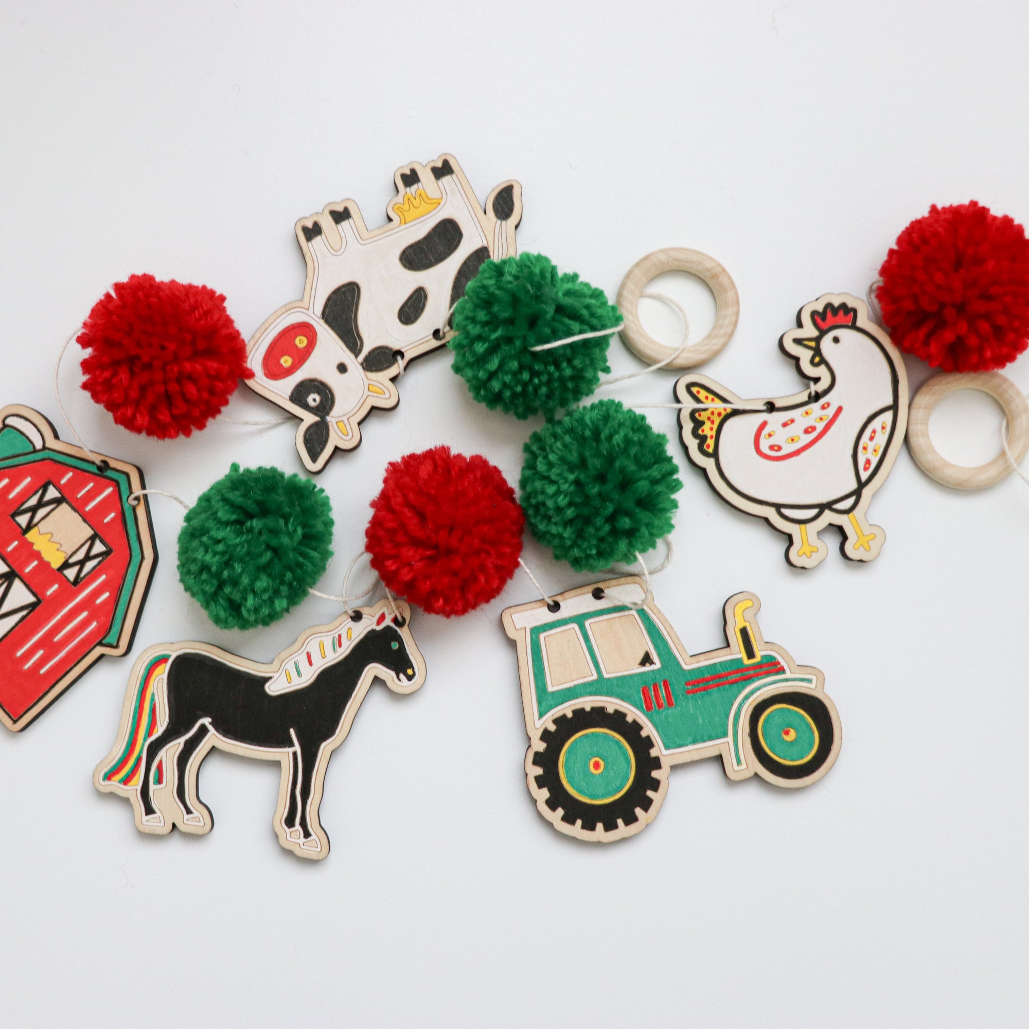 Set of colorful wooden garland pieces with pom-poms on a white background - garland craft kit made by Woodsy Craft Co.