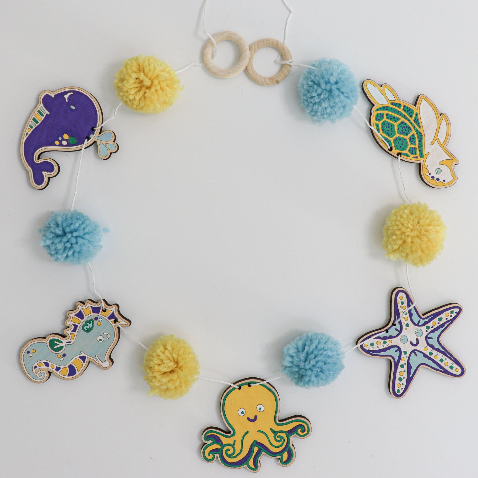 DIY kids craft kit with wooden pieces to color, pom poms and paint markers to color with.